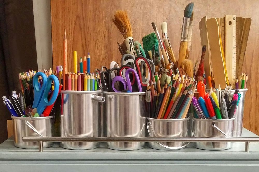 Scissors, colored pencils, markers, rulers, and paint brushes in canisters, ready to use.