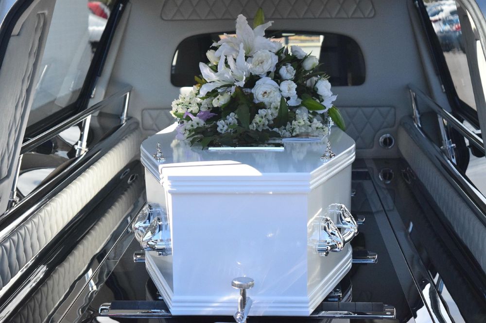 White casket with flowers in the back of a hearse
