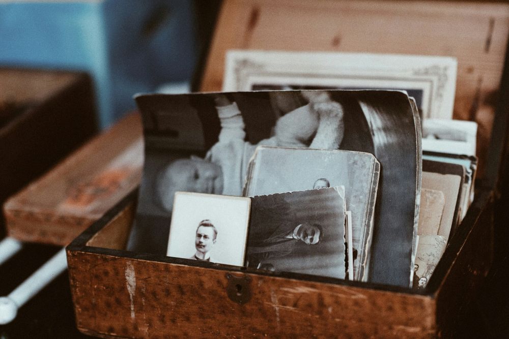 Open wooden box filled with old black and white photographs.