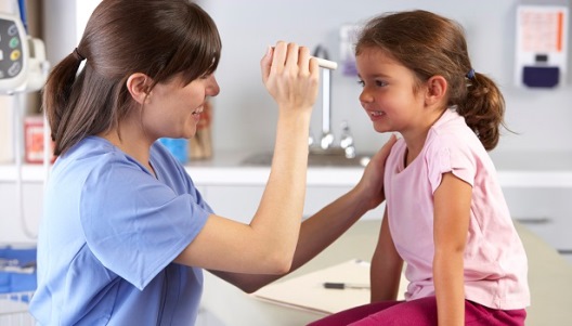 Healthcare professional examining a smiling child in a doctor's office